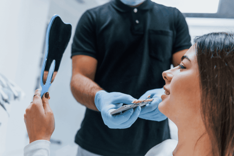 Patient examining tooth shade guide with dentist during cosmetic smile consultation.