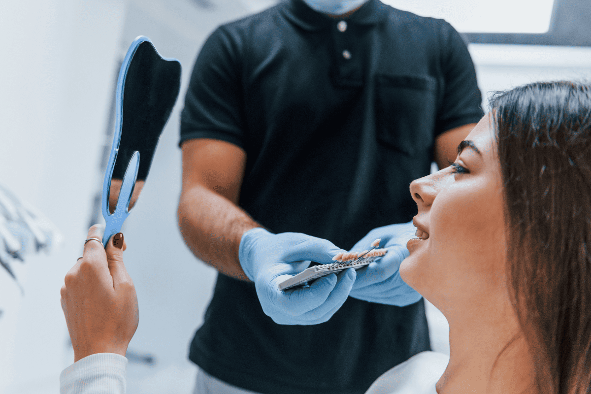 Patient examining tooth shade guide with dentist during cosmetic smile consultation.