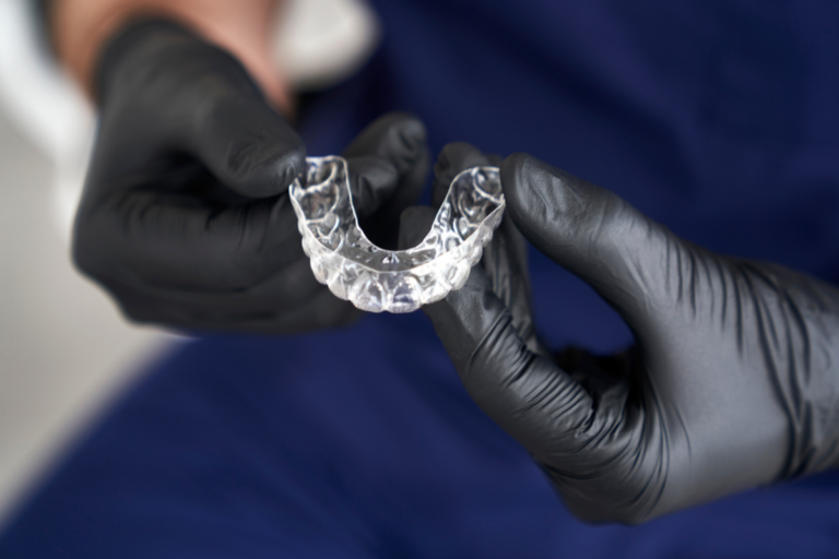 Dentist holding clear Invisalign aligner tray showing dental correction capability.